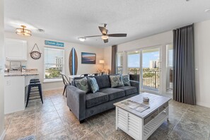 A living room with a sofa, coffee table, and a surfboard decoration.