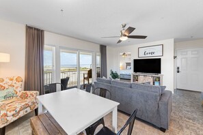 A living room with a sofa, a dining table, and a TV.