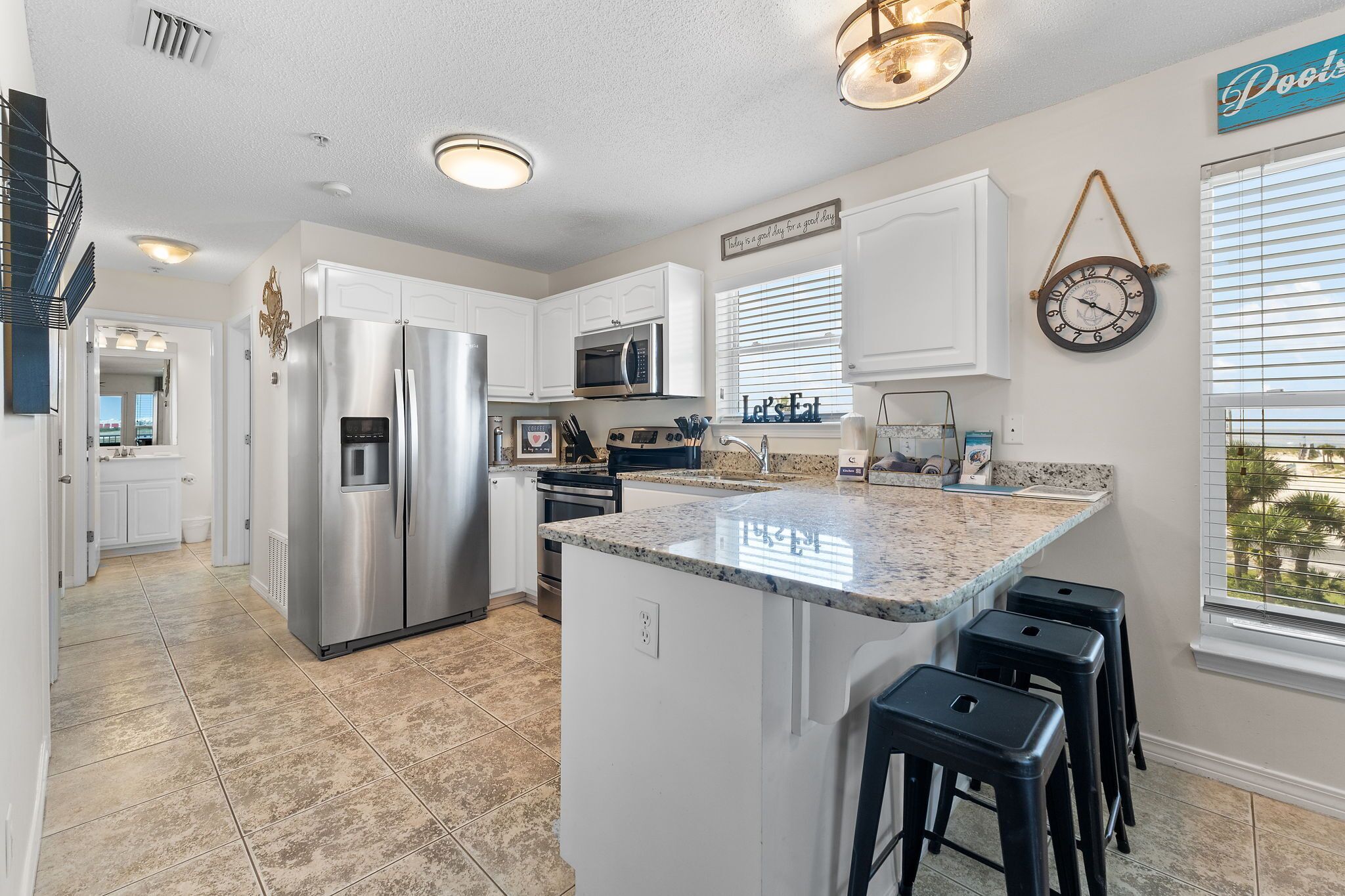 A modern kitchen with stainless steel appliances, a granite countertop, and a view of the outdoors.