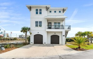 Een tweelaags huis met balkon, garage en een geplaveid pad.