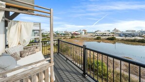 A wooden deck with a railing overlooking a water body and distant buildings. - 🐾 Sound & Sea | Pet Friendly Gated Community | Bikes + Beach Gear Navarre (Navarre)