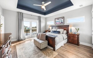 A bedroom with a bed, a nightstand, a dresser, a ceiling fan, and a view of the outside. - 🐾 Sound & Sea | Pet Friendly Gated Community | Bikes + Beach Gear Navarre (Navarre)