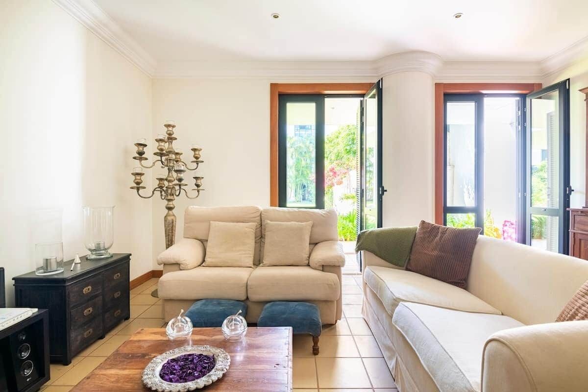 Una sala de estar con un sofá color beige, una mesa de centro de madera y un candelabro decorativo.