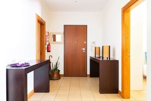 A hotel lobby with a reception desk, a wooden door, a fire extinguisher, and a potted plant. - SunDream Apart I (Funchal)