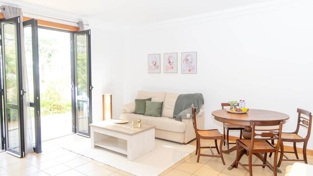 A living room with a sofa, coffee table, and dining table with chairs. - SunDream Apart II (Funchal)