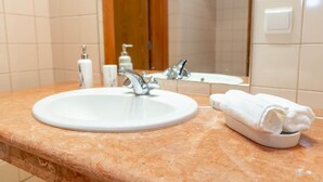 A bathroom with a white sink, a mirror, a towel rack, and toiletries. - SunDream Apart II (Funchal)