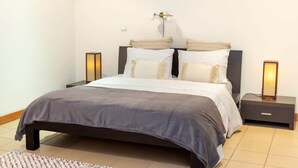 A modern bedroom with a bed, nightstands, and a wall-mounted lamp. - SunDream Apart II (Funchal)