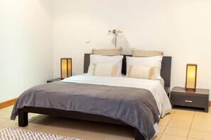 Ein modernes Schlafzimmer mit einem Bett, Nachttischen und einer Wandleuchte.