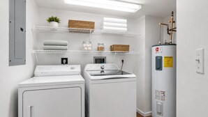 A laundry room with two front-loading washing machines, a stacked washer and dryer, and a water heater. - Oceanfront 3BR Balcony Indoor Outdoor Pools (Daytona Beach Shores)