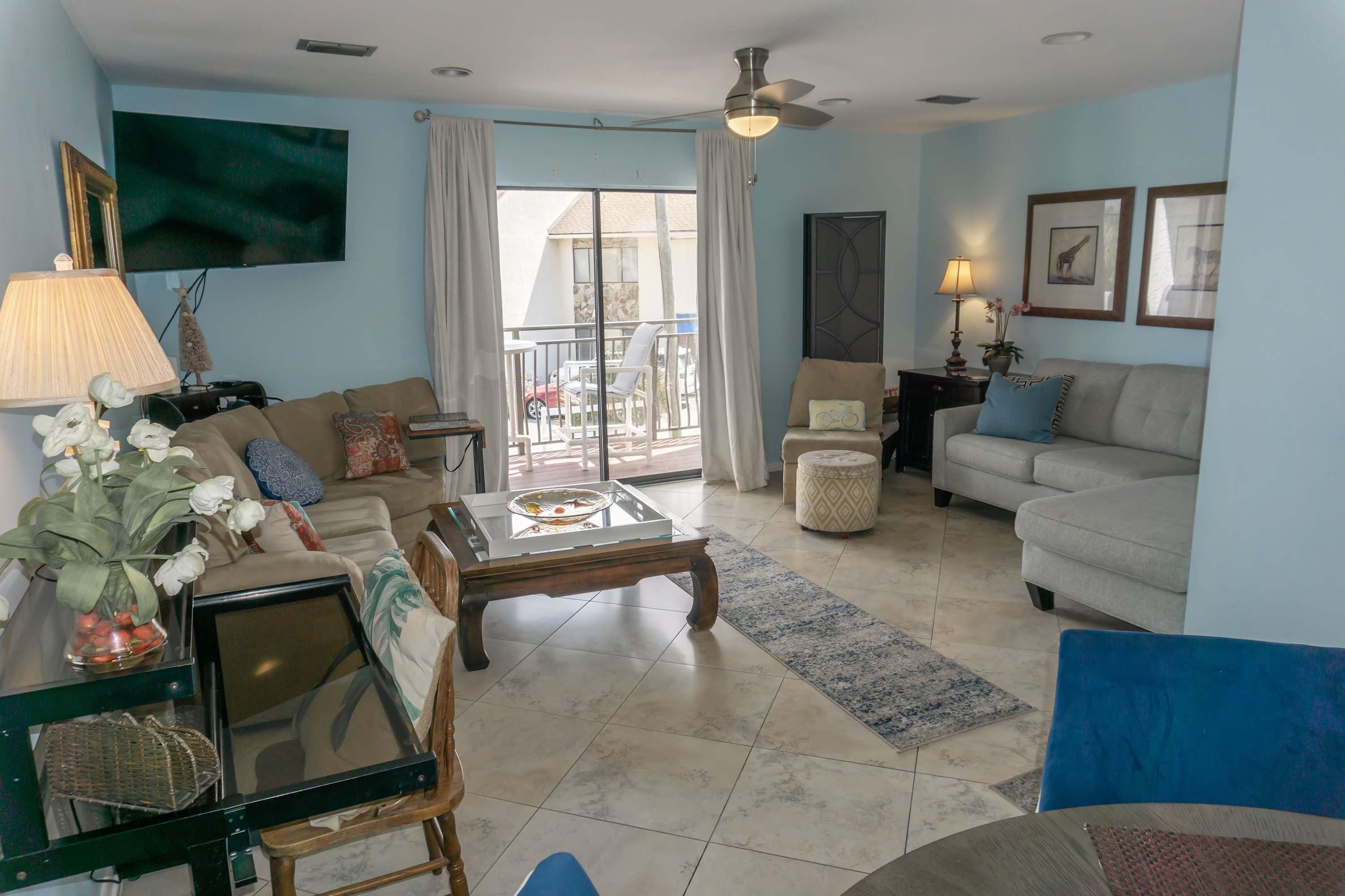 Sala de estar con sofá, mesa de centro y televisor. Balcón con vistas al exterior.
