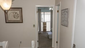 A hallway with a framed artwork on the left, a door with a light switch on the right, and a staircase leading to a balcony. - Beachfront Villa With Sea Views Bikes Included Gulf Across St Kayak Access (Miramar Beach)