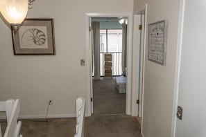 A hallway with a framed artwork on the left, a door with a light switch on the right, and a staircase leading to a balcony. - Beachfront Villa With Sea Views Bikes Included Gulf Across St Kayak Access (Miramar Beach)