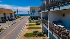 A multi-story building with balconies, a parking lot, and a clear view of the ocean. - Beachfront Villa With Sea Views Bikes Included Gulf Across St Kayak Access (Miramar Beach)
