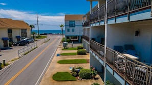 A multi-story building with balconies, a parking lot, and a clear view of the ocean. - Beachfront Villa With Sea Views Bikes Included Gulf Across St Kayak Access (Miramar Beach)
