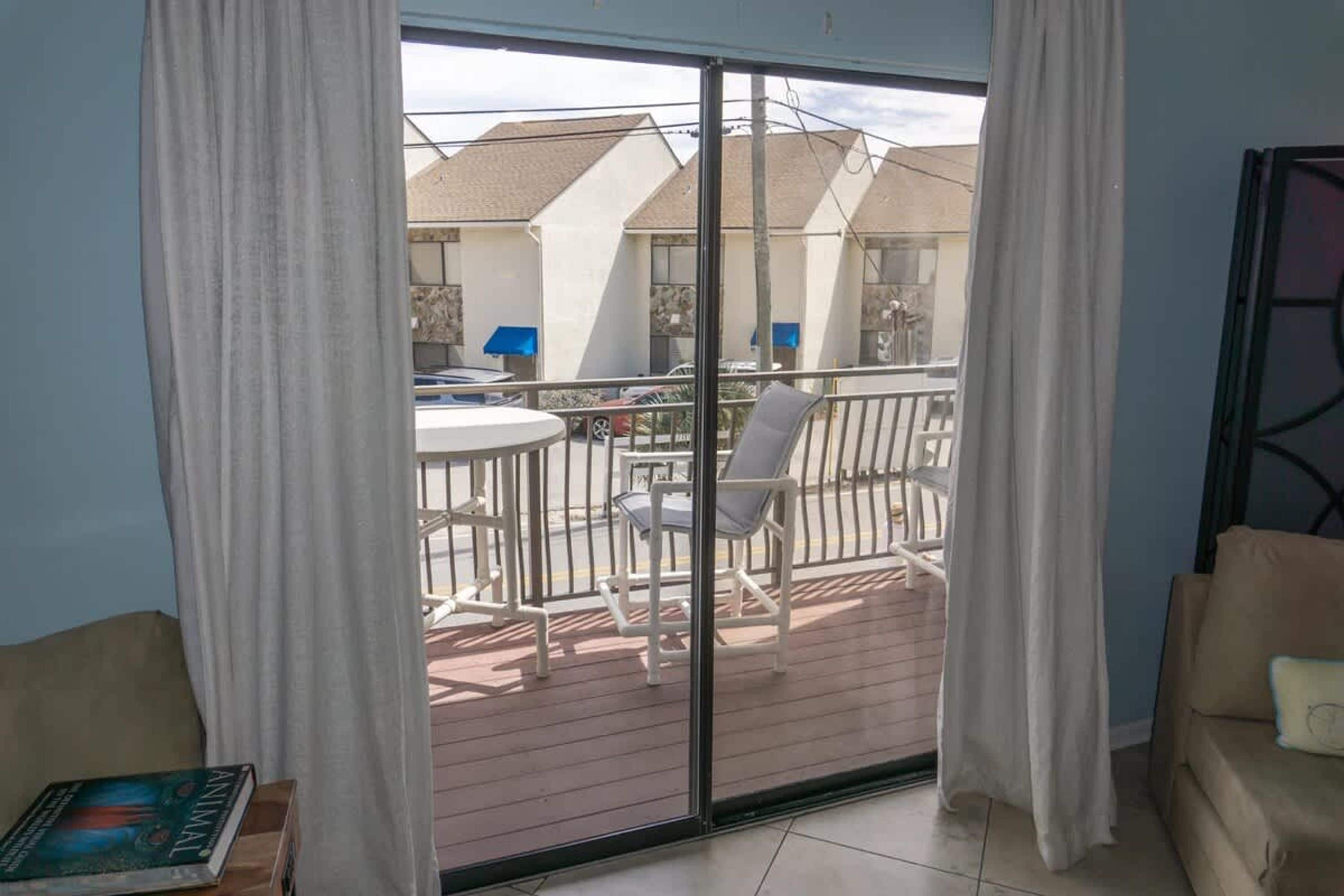A room with a sliding glass door leading to an outdoor patio area with a table and chairs.
