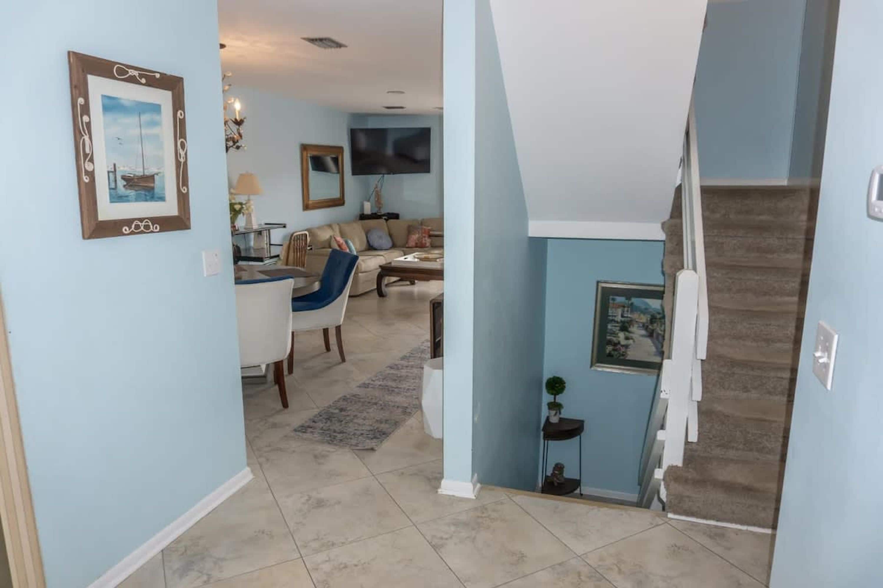 Un salon avec un canapé, une table basse et un téléviseur. Un escalier mène à un autre niveau.