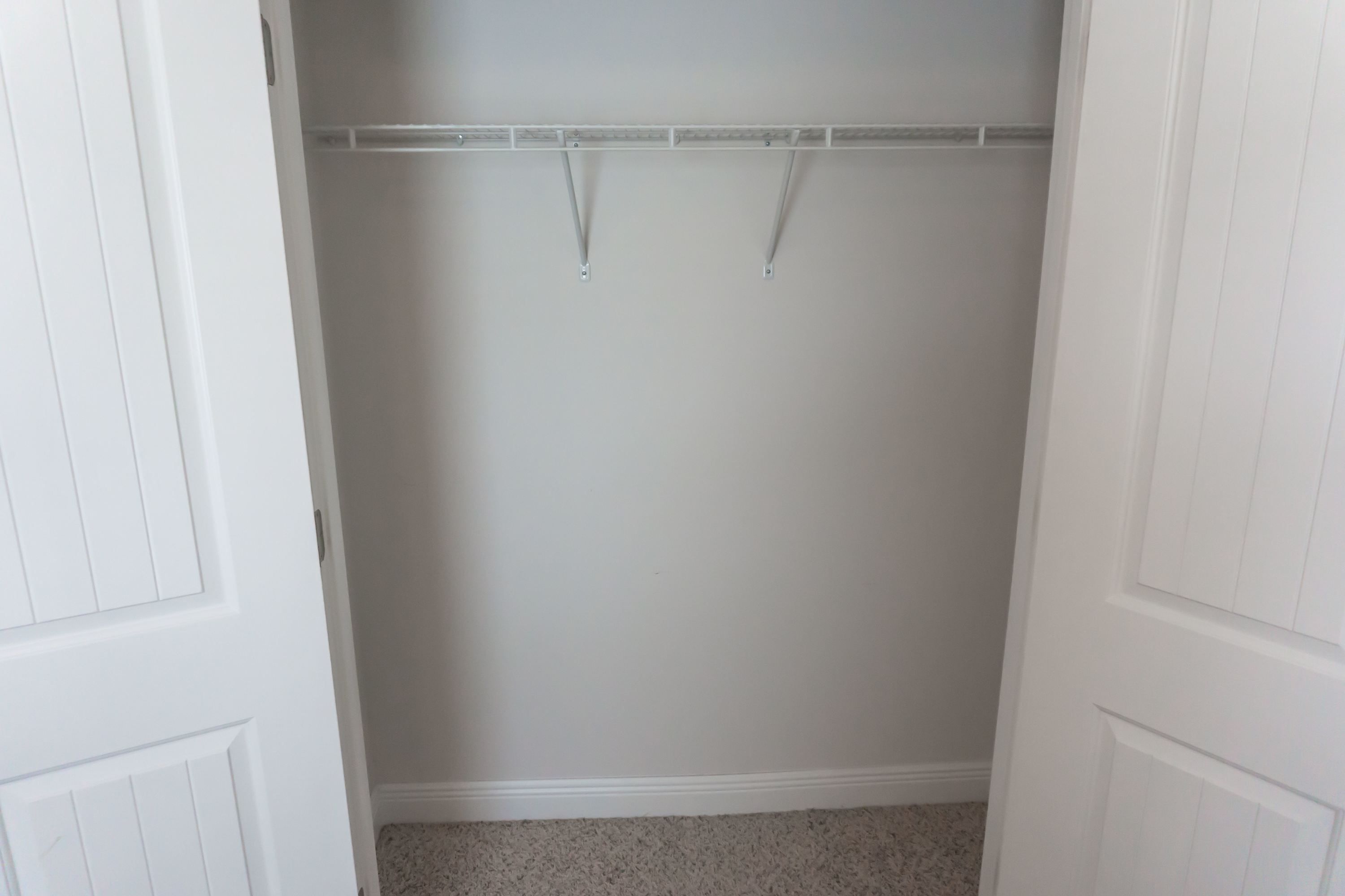 Un armario blanco con barra y puerta.