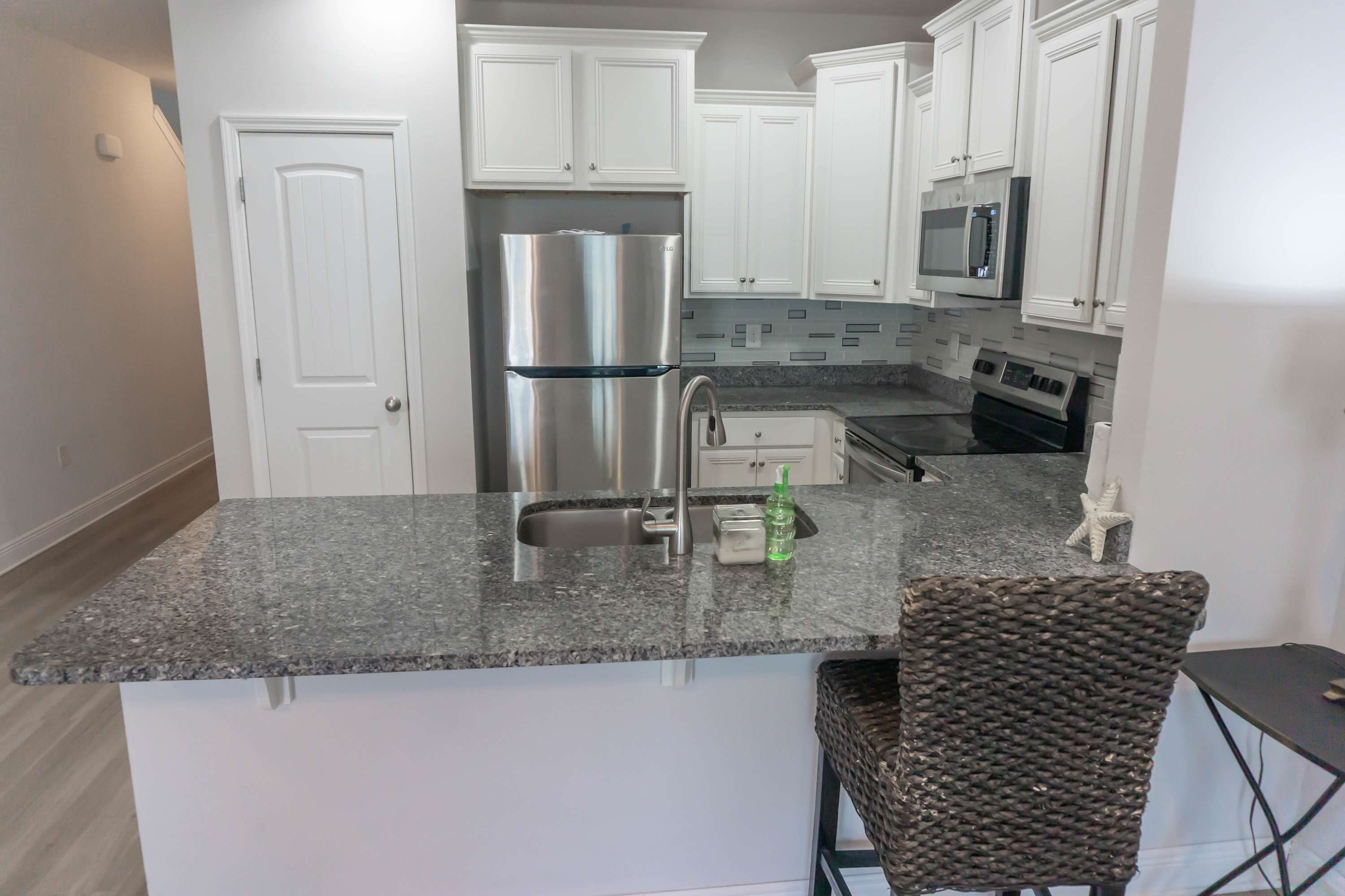 A kitchen with white cabinets, a stainless steel refrigerator, a microwave, and a stove.