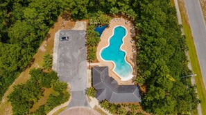 Vista aerea di una proprietà con piscina, area parcheggio e vegetazione circostante.