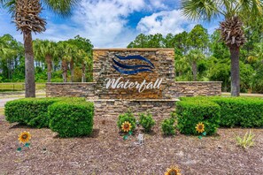 A stone wall with the word 'Waterfall' and a stylized water design. - Waterfall Community 109 Harmony Falls Lane Pets OK (Panama City Beach)