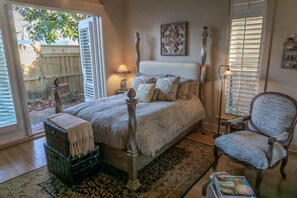 A bedroom with a four-poster bed, a chair, a small table, and a window with blinds. - Gated Beach Villa w 2 Pools 3 Bikes Included Tennis Pickleball Courts Included (Miramar Beach)
