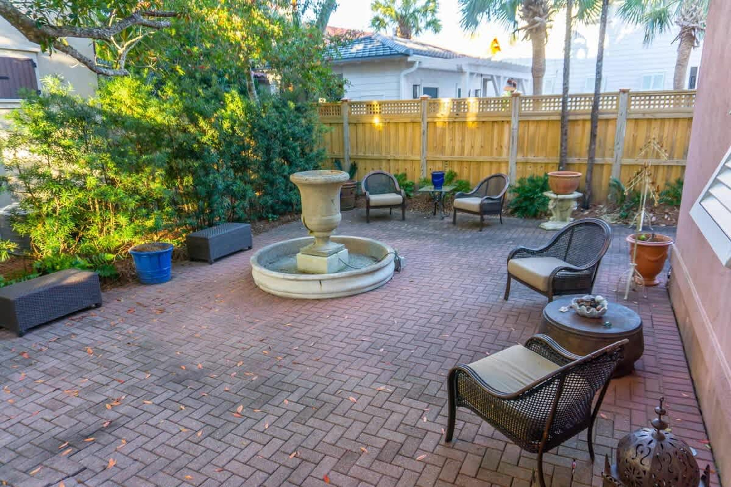 A patio with a fountain, seating, and potted plants.