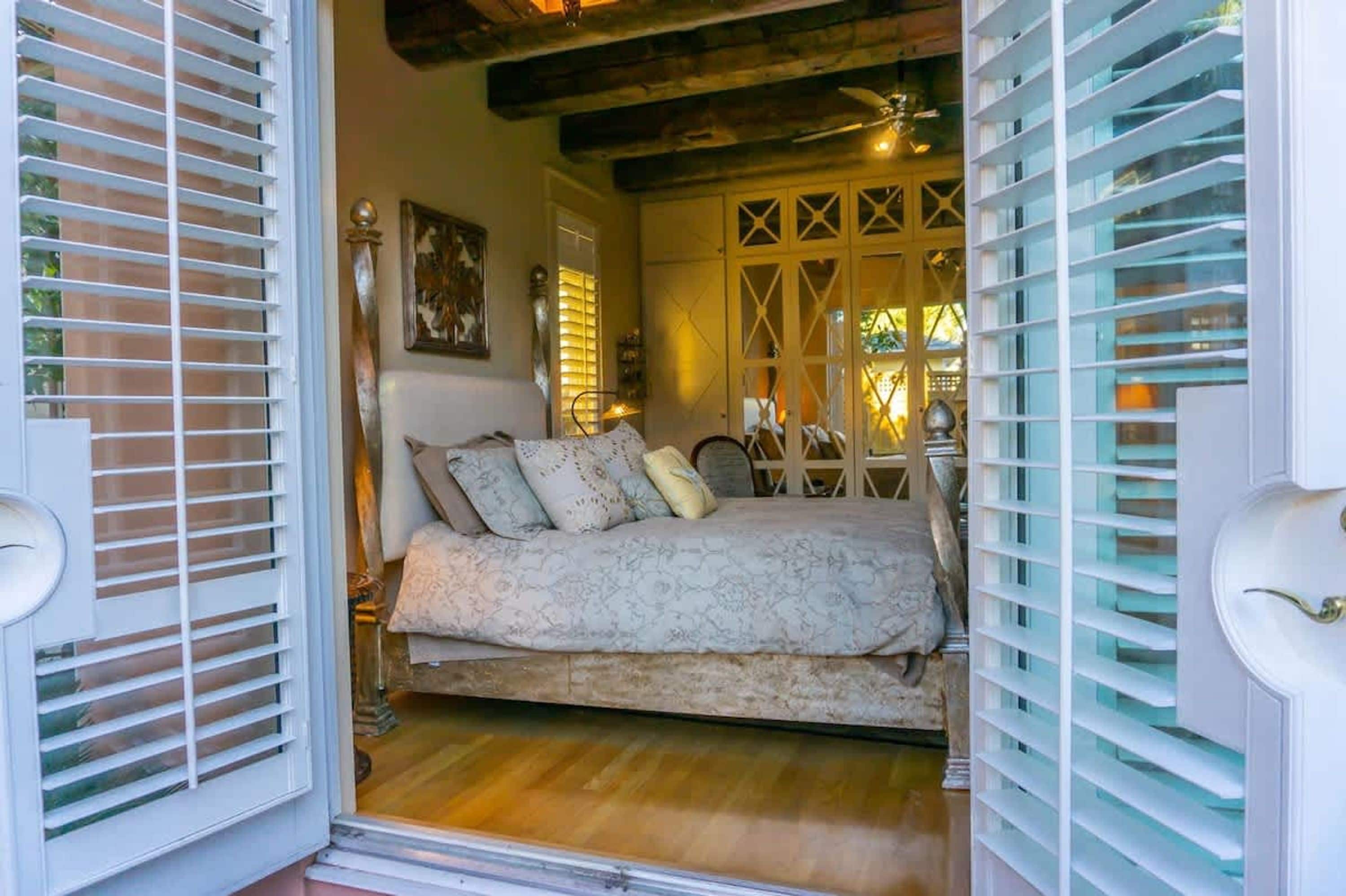 A bedroom with a bed, a nightstand, a lamp, and a window with blinds.