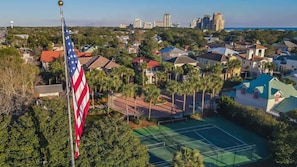 A residential area with houses, a tennis court, and an American flag. - Gated Beach Villa w 2 Pools 3 Bikes Included Tennis Pickleball Courts Included (Miramar Beach)