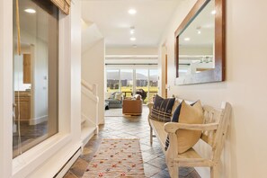 Un couloir avec un banc, un tapis et une vue sur l’extérieur.