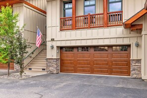A two-story house with a stone foundation, a wooden balcony, and a double garage.