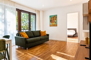 A modern living room with a sofa, a dining table, and a painting on the wall. - Elegantis Luce di Trastevere Apartment with Terrace (Roma)
