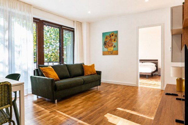 Ein modernes Wohnzimmer mit einer Couch, einem Esstisch und einem Bild an der Wand.