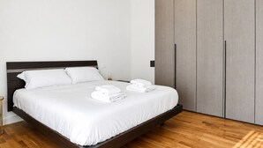 Een moderne slaapkamer met een groot bed, een houten hoofdbord en een kledingkast.