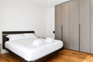 Ein modernes Schlafzimmer mit einem großen Bett, einem Holz-Kopfteil und einem Kleiderschrank.