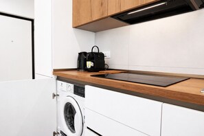 Eine kleine Küche mit integriertem Waschmaschine, einer Holz Arbeitsplatte und einer schwarzen Tasche auf der Arbeitsfläche.