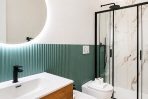 Ein modernes Badezimmer mit einem weißen Waschbecken, einer Toilette und einer Duschkabine aus Glas.