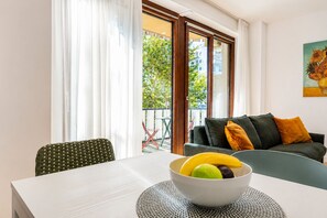 Ein Essbereich mit Tisch, Stühlen, einer Obstschale und Blick ins Freie durch eine Schiebetür.