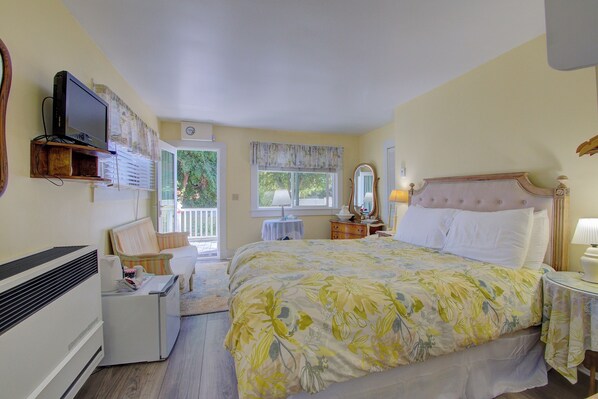 Een slaapkamer met een bed, een televisie, een dressoir en een raam.