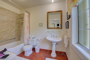 Een badkamer met een bad, toilet, wastafel en douchegordijn.