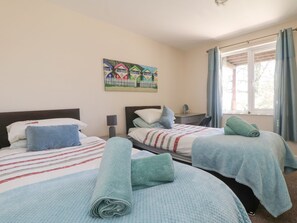 A hotel room with two beds, a painting on the wall, a desk, and a window with curtains. - Honeycombe Lodge (Gunnislake)