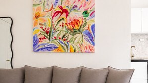 Ein Wohnzimmer mit einem beigen Sofa und einem farbenfrohen floralen Gemälde an der Wand.