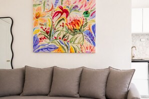 Ein Wohnzimmer mit einem beigen Sofa und einem farbenfrohen floralen Gemälde an der Wand.