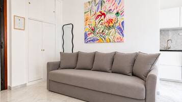 Un divano dai toni neutri in un soggiorno moderno, con un quadro astratto dai colori vivaci appeso alla parete.