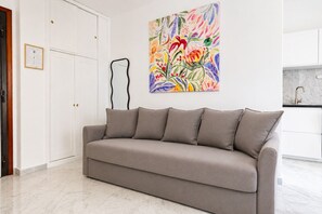 A neutral-toned sofa in a modern living area with a colorful abstract painting on the wall. - Elegantis Trastevere Suite with Terrace - Comfort in Most Charming District (Roma)