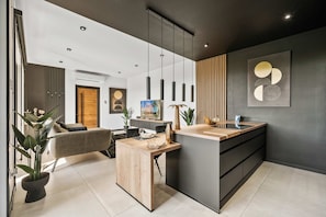 A modern living room with a sofa, coffee table, and a dining area with a wooden table and chairs. - Hooiberg 49 U Apt 1 Pearl House (Oranjestad)