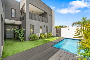 Ein modernes, zweistöckiges Haus mit Schwimmbad, gepflegtem Rasen und verschiedenen Pflanzen.
