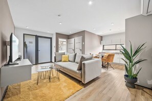 Ein modernes Wohnzimmer mit einer Couch, einem Couchtisch und einem Essbereich mit Stühlen.