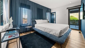 Ein modernes Schlafzimmer mit einem großen Bett, einem Schreibtisch mit Stuhl und einem Fenster mit Vorhängen.