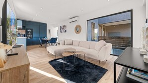 Ein modernes Wohnzimmer mit Ecksofa, Couchtisch und Essbereich mit Stühlen.