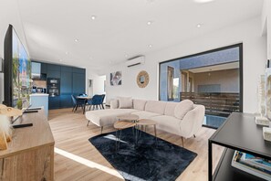 Ein modernes Wohnzimmer mit Ecksofa, Couchtisch und Essbereich mit Stühlen.